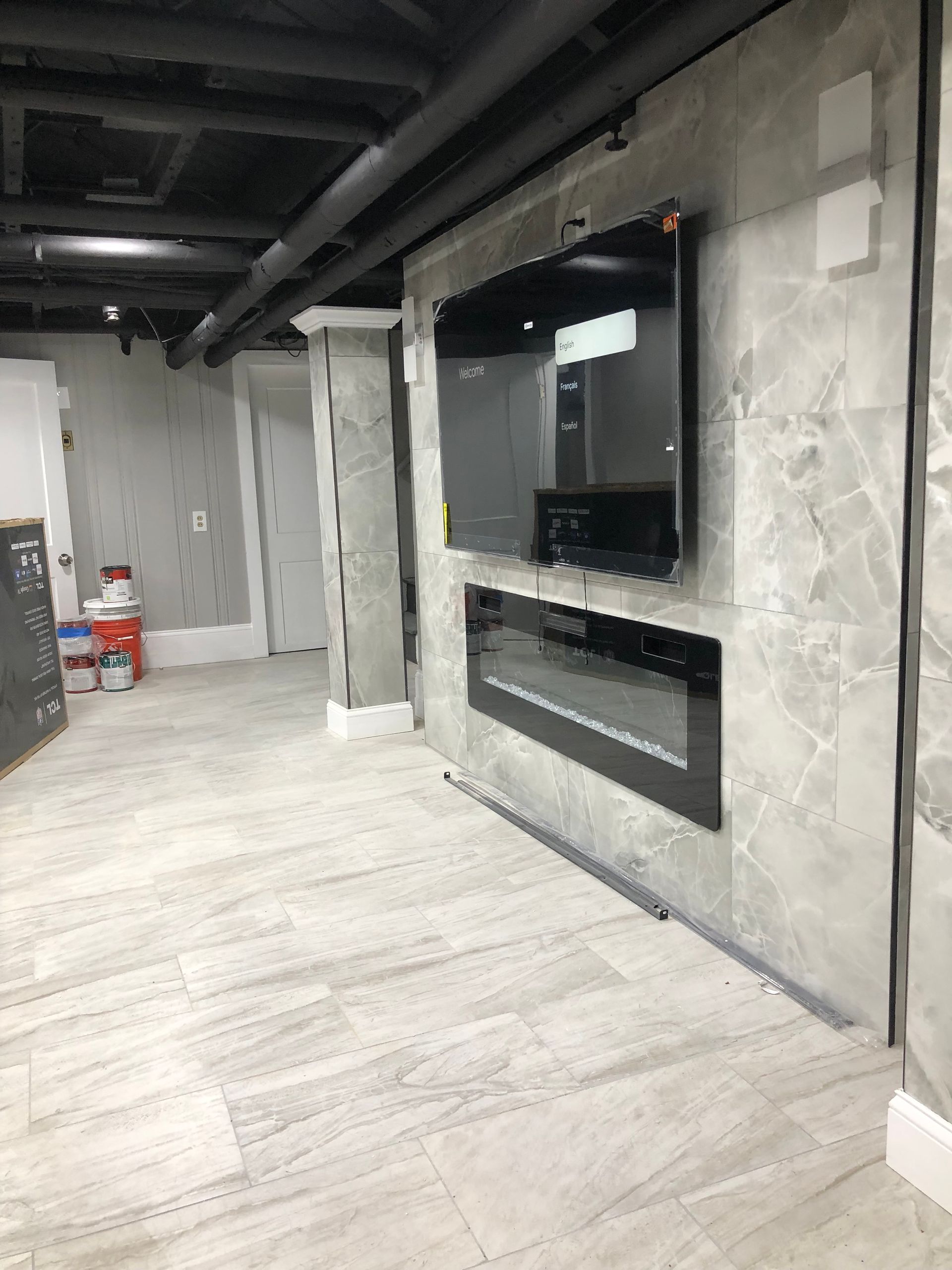 Unfinished modern basement with concrete walls, light wood floor, and a recessed wall-mounted TV area