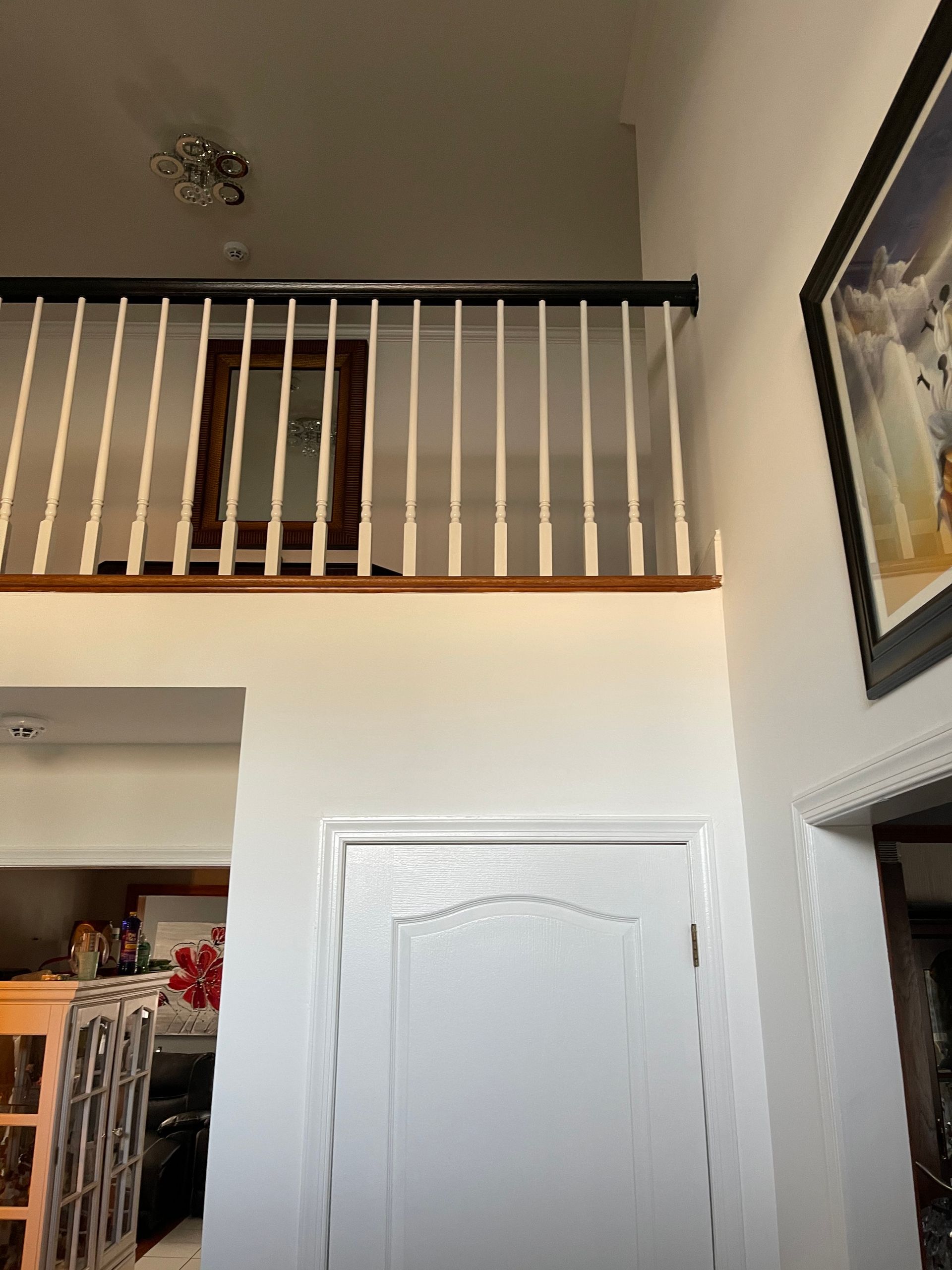 Interior hallway with white railing overlooking an entryway and a framed picture on the wall