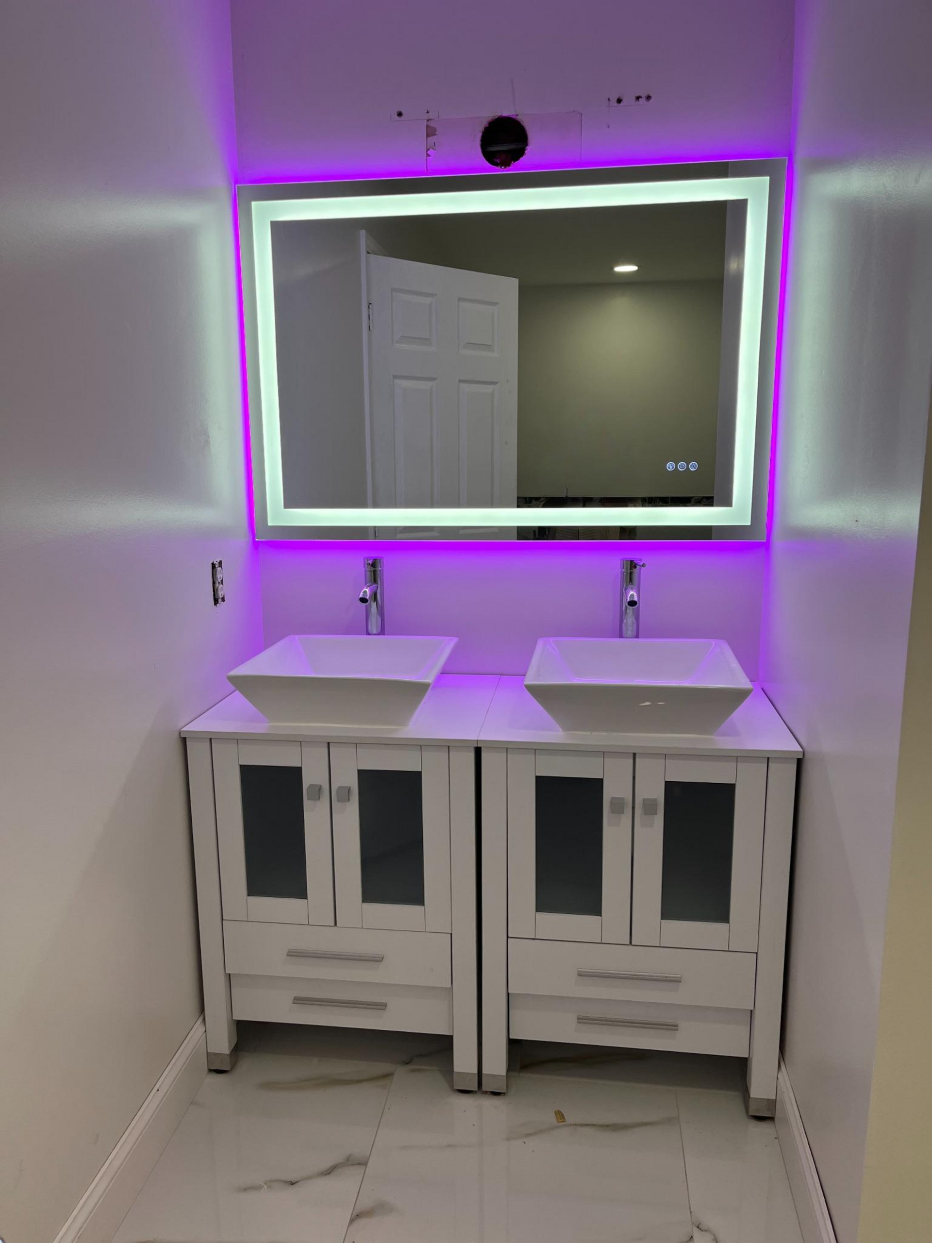 Modern bathroom with dual sinks, illuminated mirror, and purple LED lighting