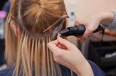 Hairdresser using a curling iron on blonde hair with clips in a salon.