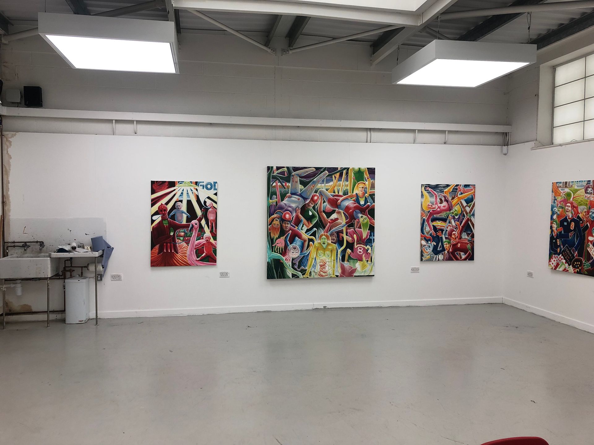 Art gallery with colorful abstract paintings on white walls in a bright, mostly empty room