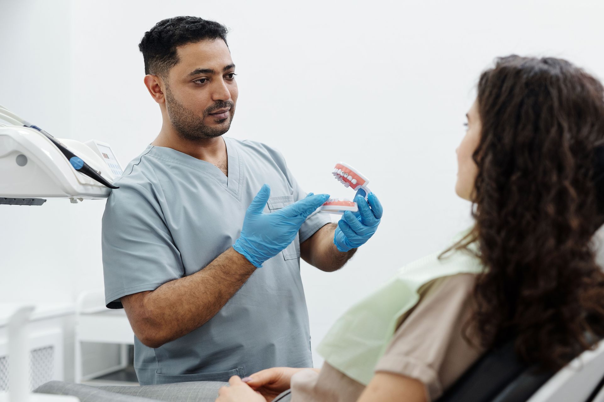 Dentist showing patient a model of a mouth with gums and teeth, discussing details