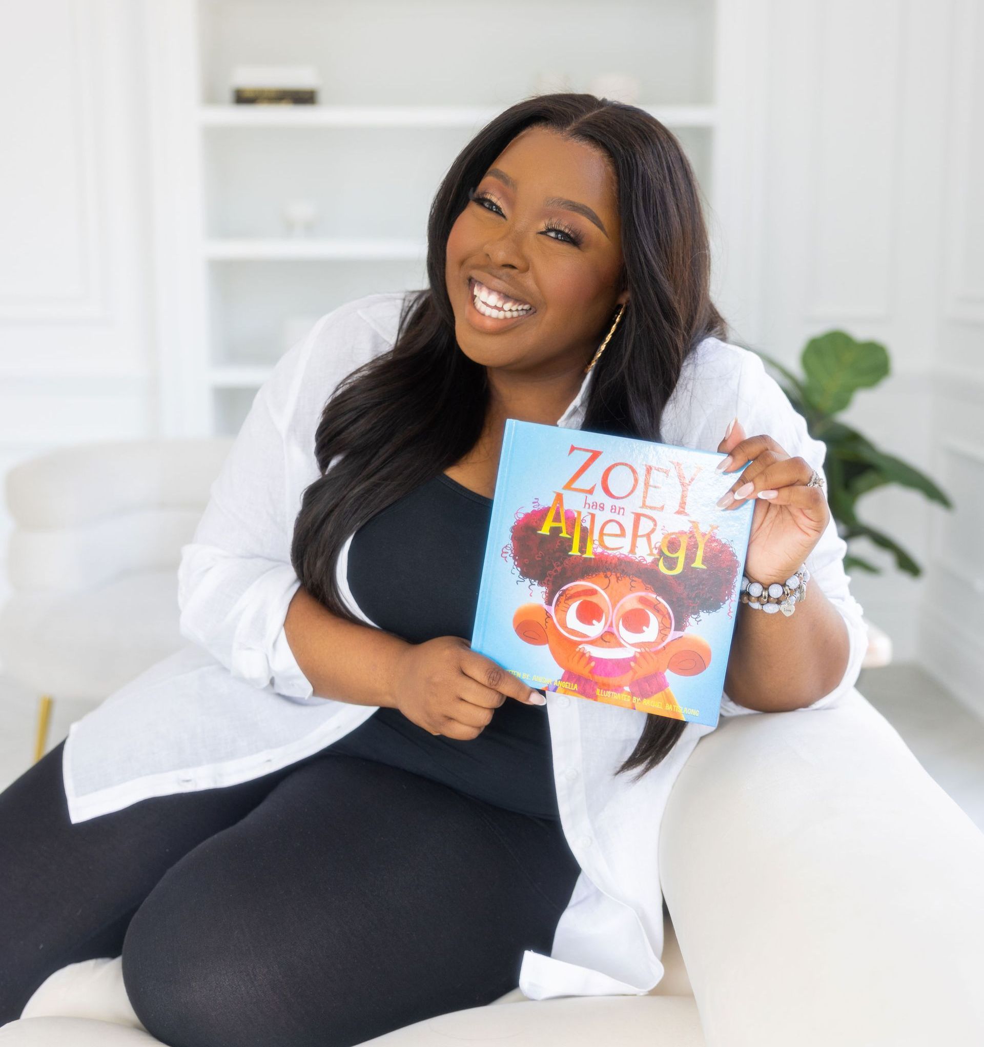Anisha Angella author holding her book Zoey has an Allergy