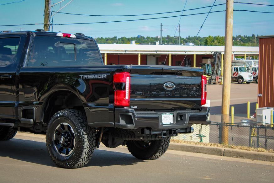 A black Ford Tremor pickup truck viewed from the rear, parked on an asphalt lot near a building.
