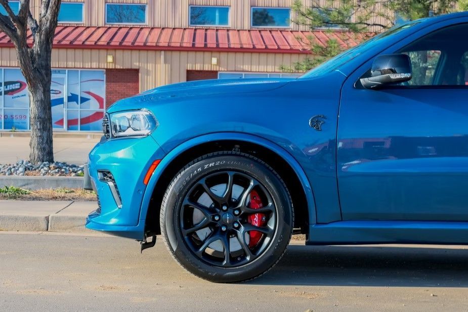 A close-up side view of a blue Dodge Durango SRT parked on an asphalt street in front of a building.