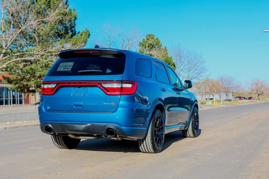 A blue Dodge Durango parked on an asphalt road under a clear blue sky.