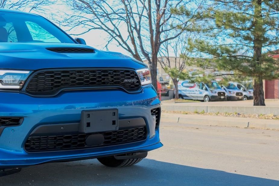 A close-up of a blue Dodge Durango SUV parked outdoors with trees in the background.