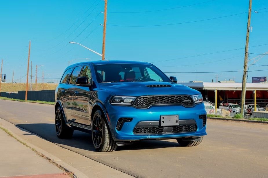 A blue Dodge Durango SUV parked on a paved road under a clear blue sky.