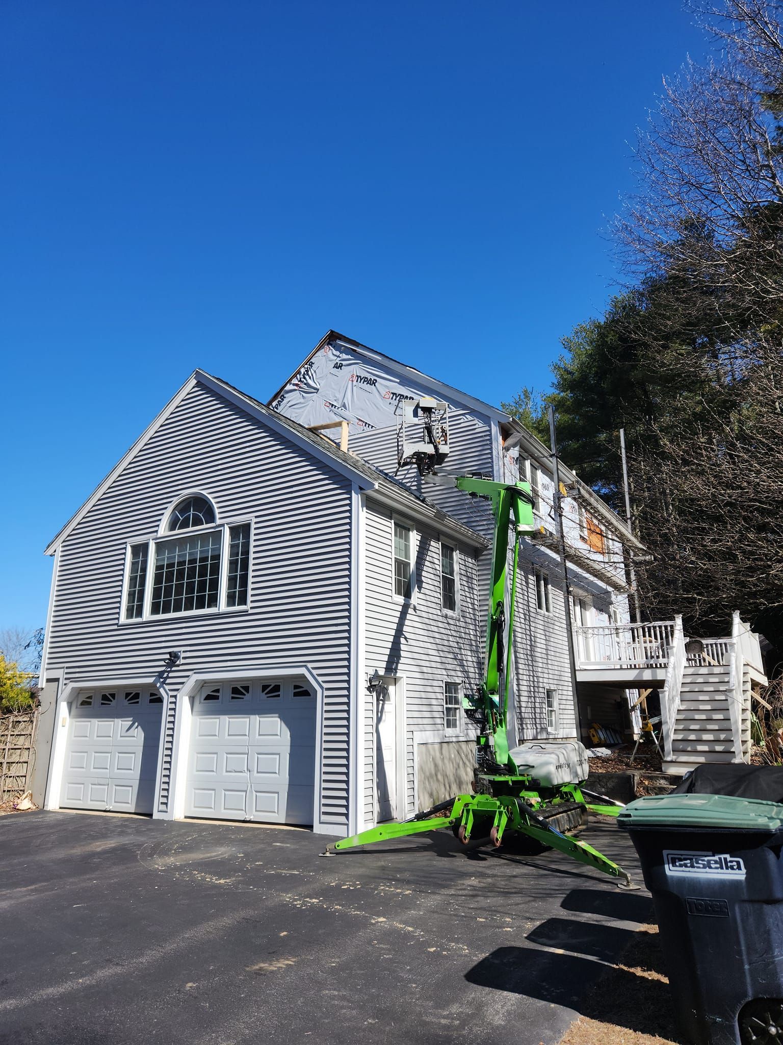 A large white house with a green lift in front of it.
