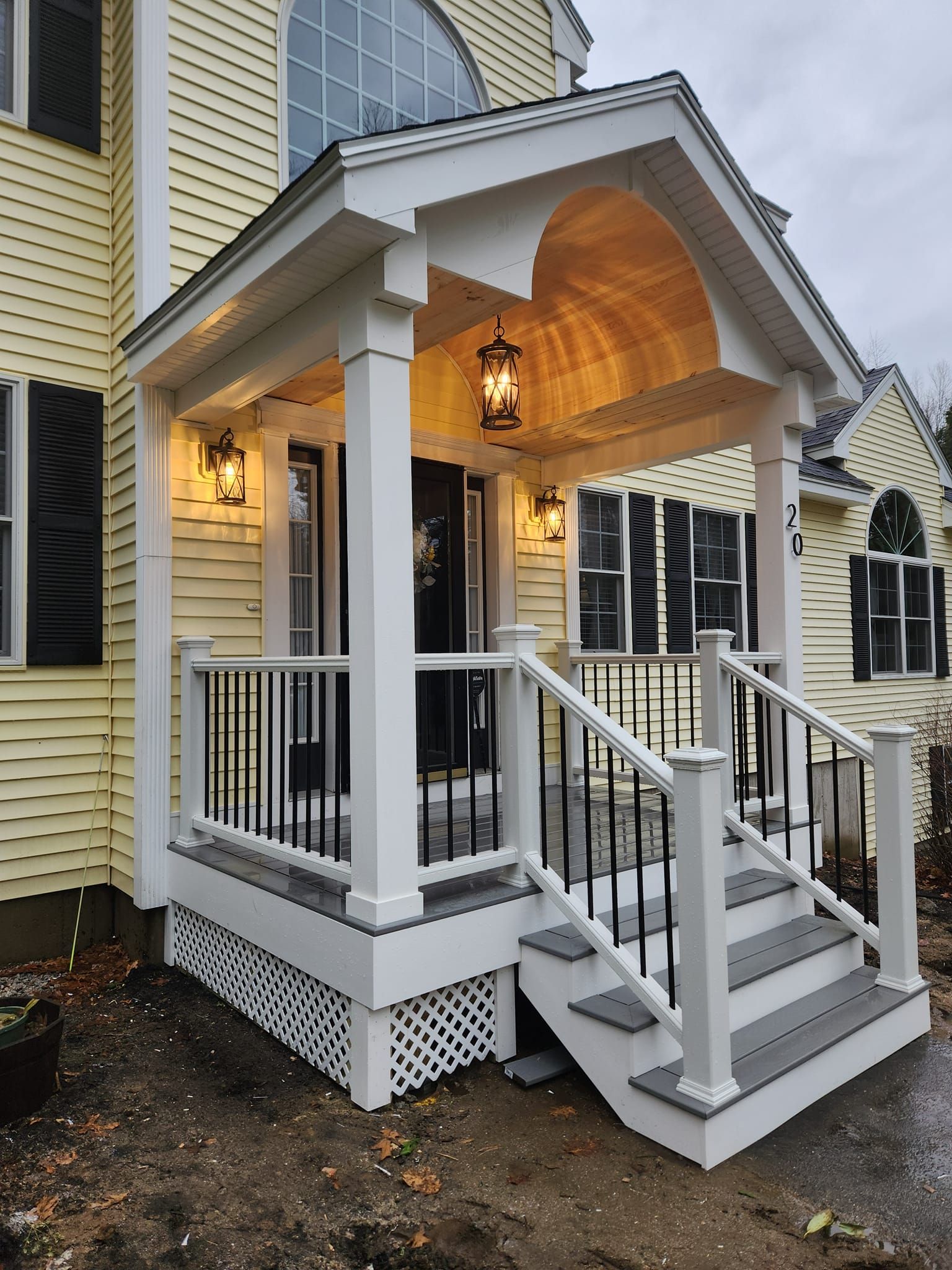 A yellow house with a white porch and stairs