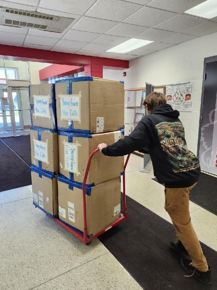 A man is pushing a cart full of cardboard boxes.