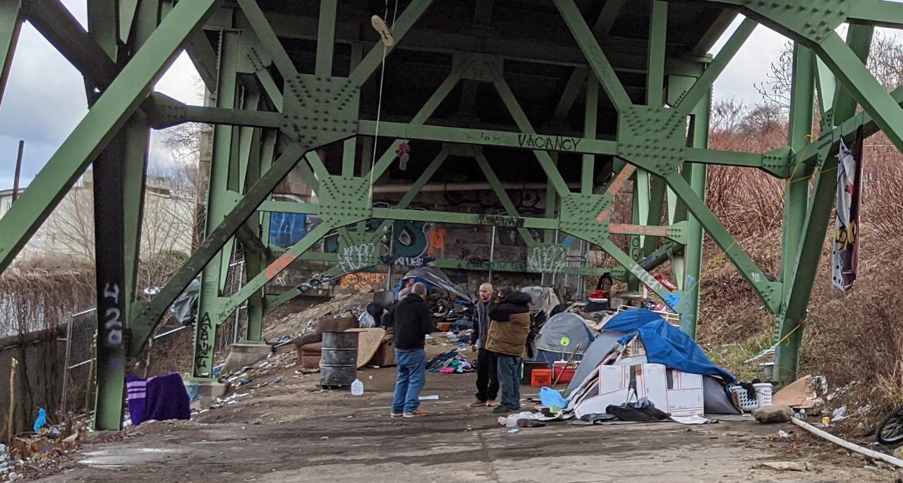 A group of people are standing under a bridge.