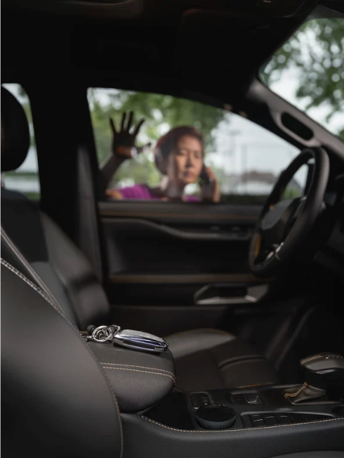 Woman locked out of a car, reaching for keys on the center console. Interior shot, dark gray seats, bright outside.