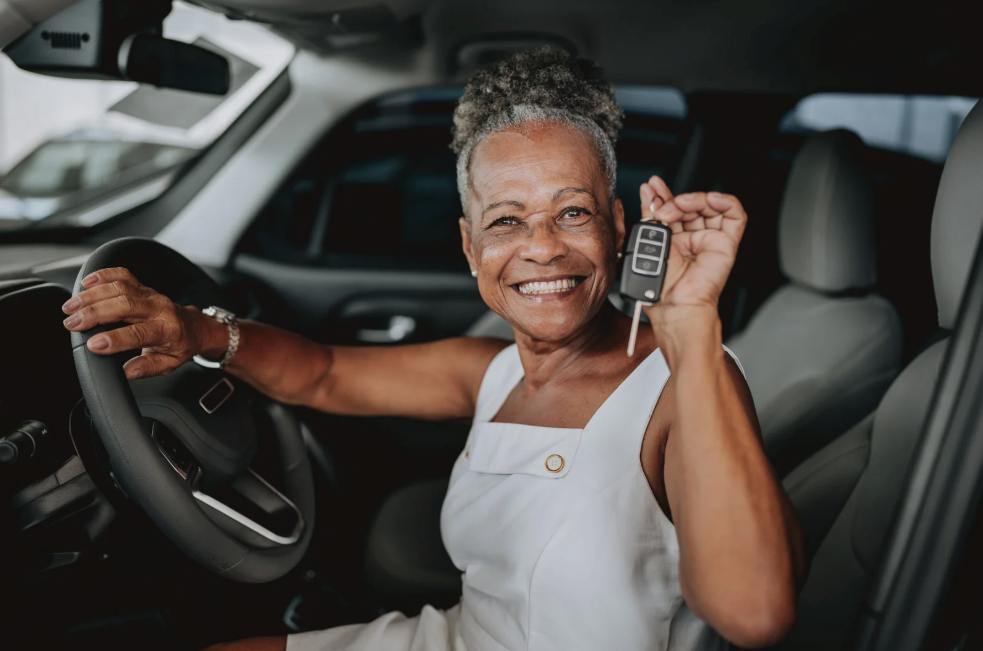 Woman in car holding up car keys, smiling.