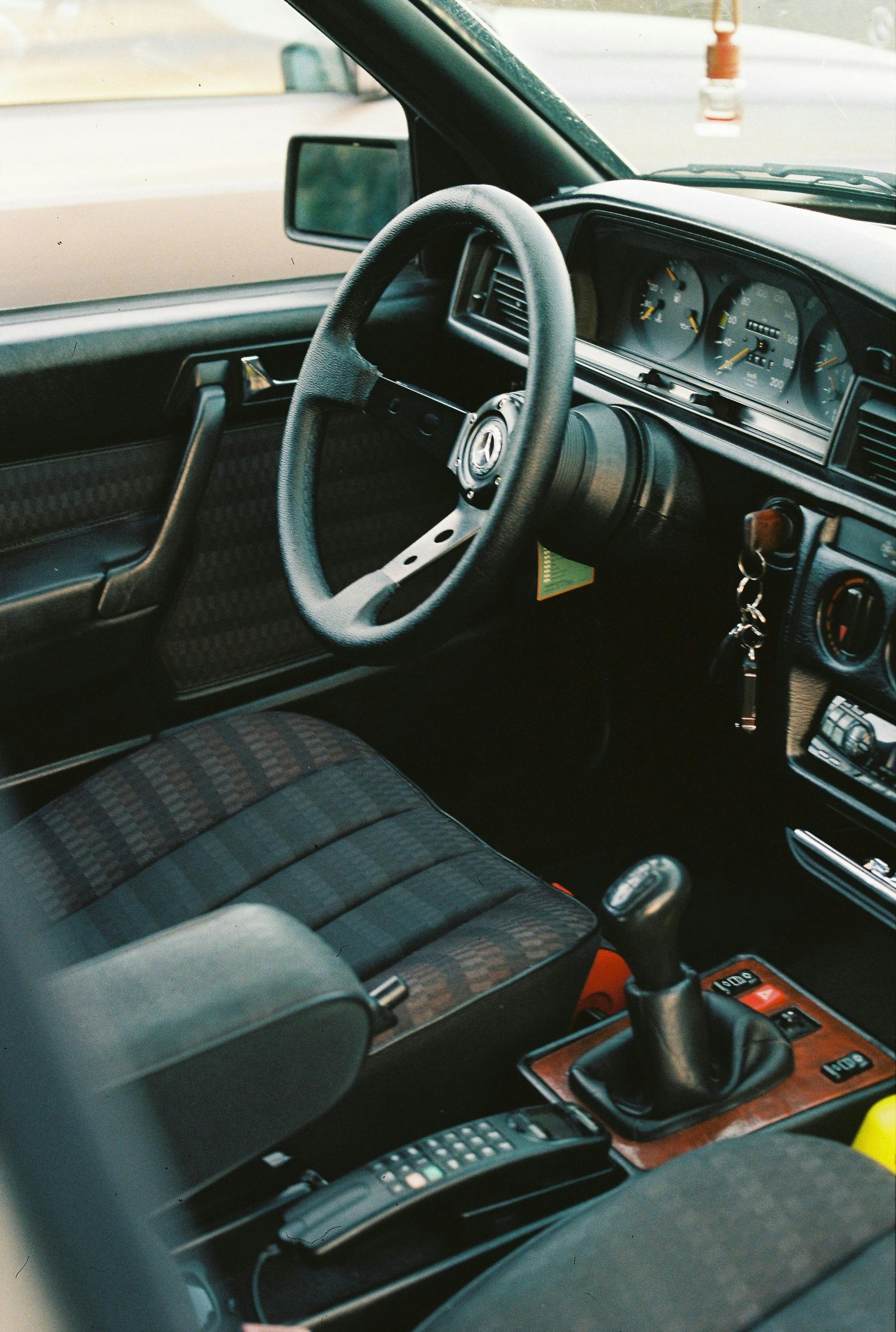 Interior of a black car with a sporty steering wheel and gearshift. Dark upholstery and dashboard details.