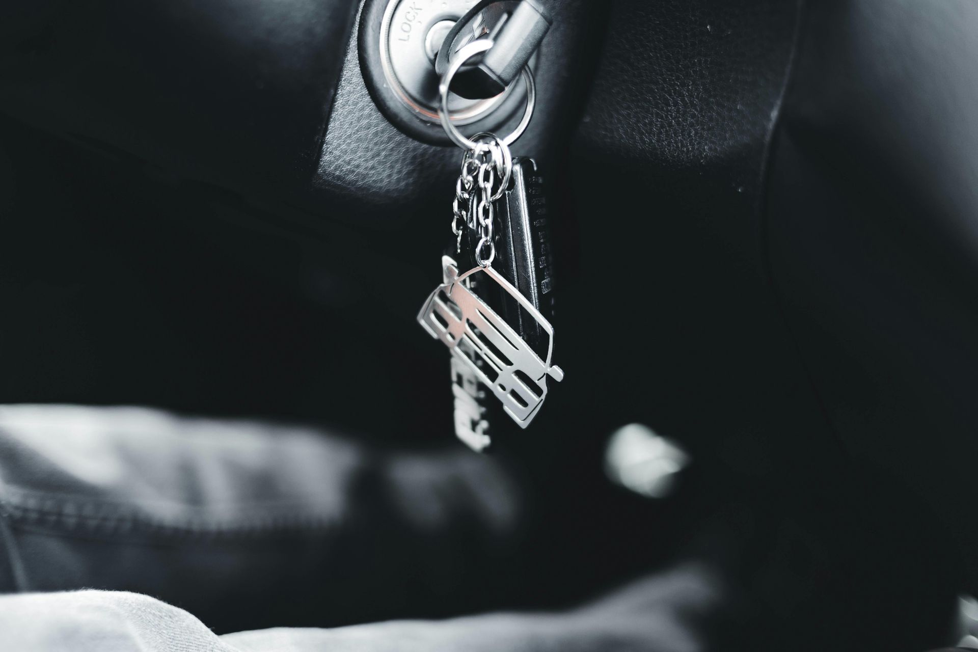 Car keys in the ignition, dangling from a silver keychain. Black and white, close-up.