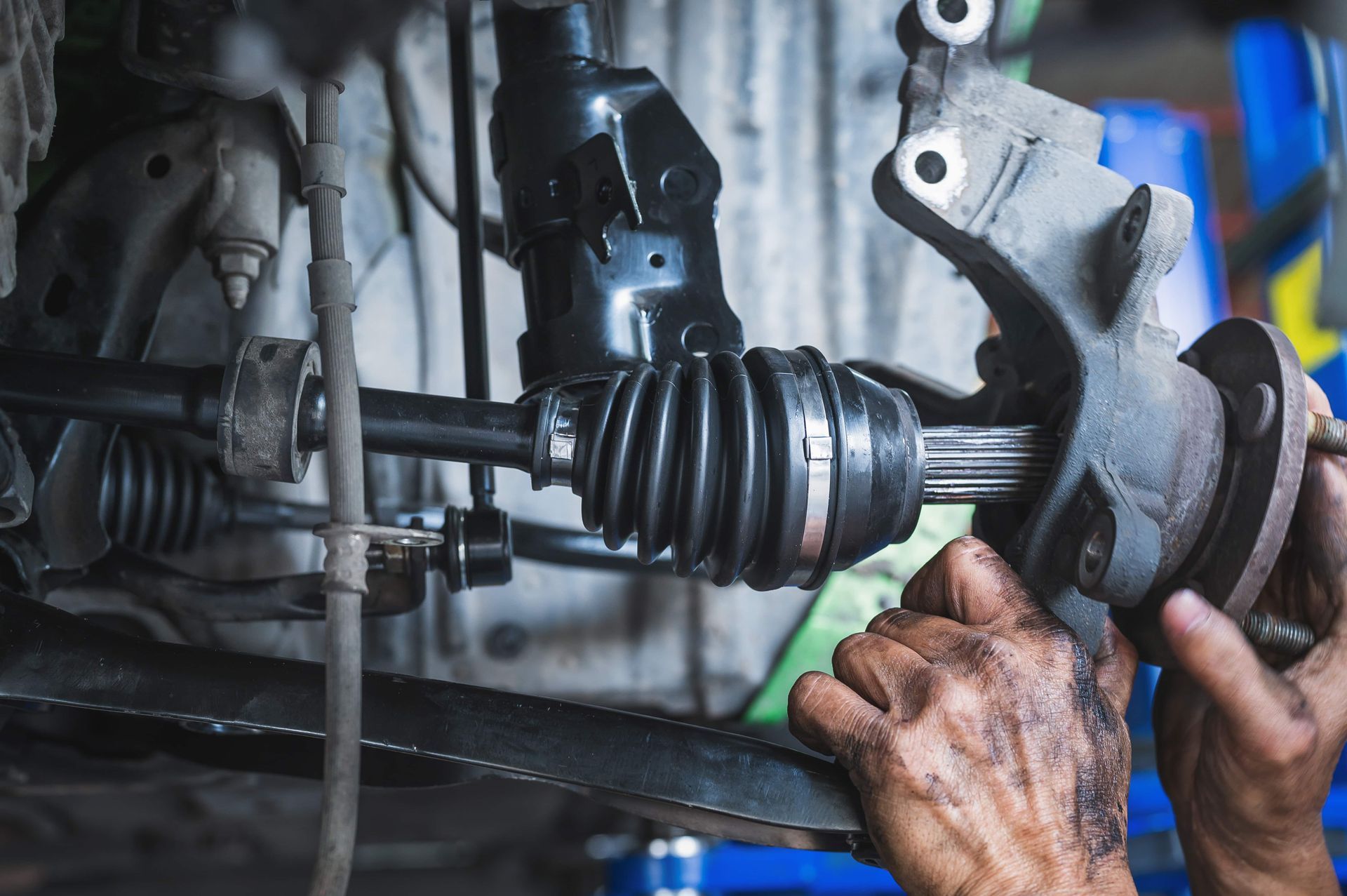 A person is working on a drive shaft on a car.