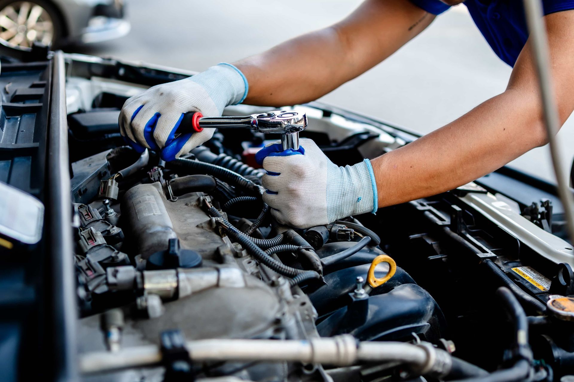A man is working on the engine of a car with a wrench.