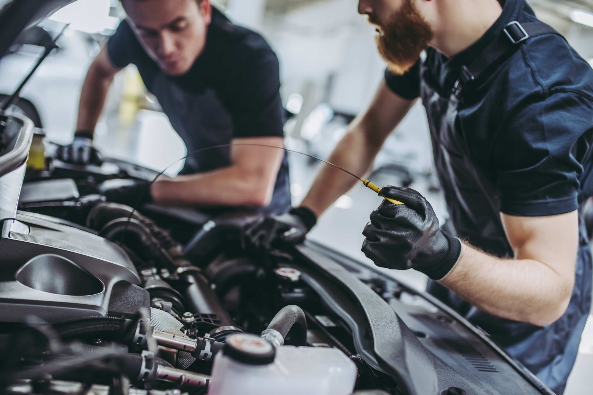 Two mechanics are working on a car in a garage.