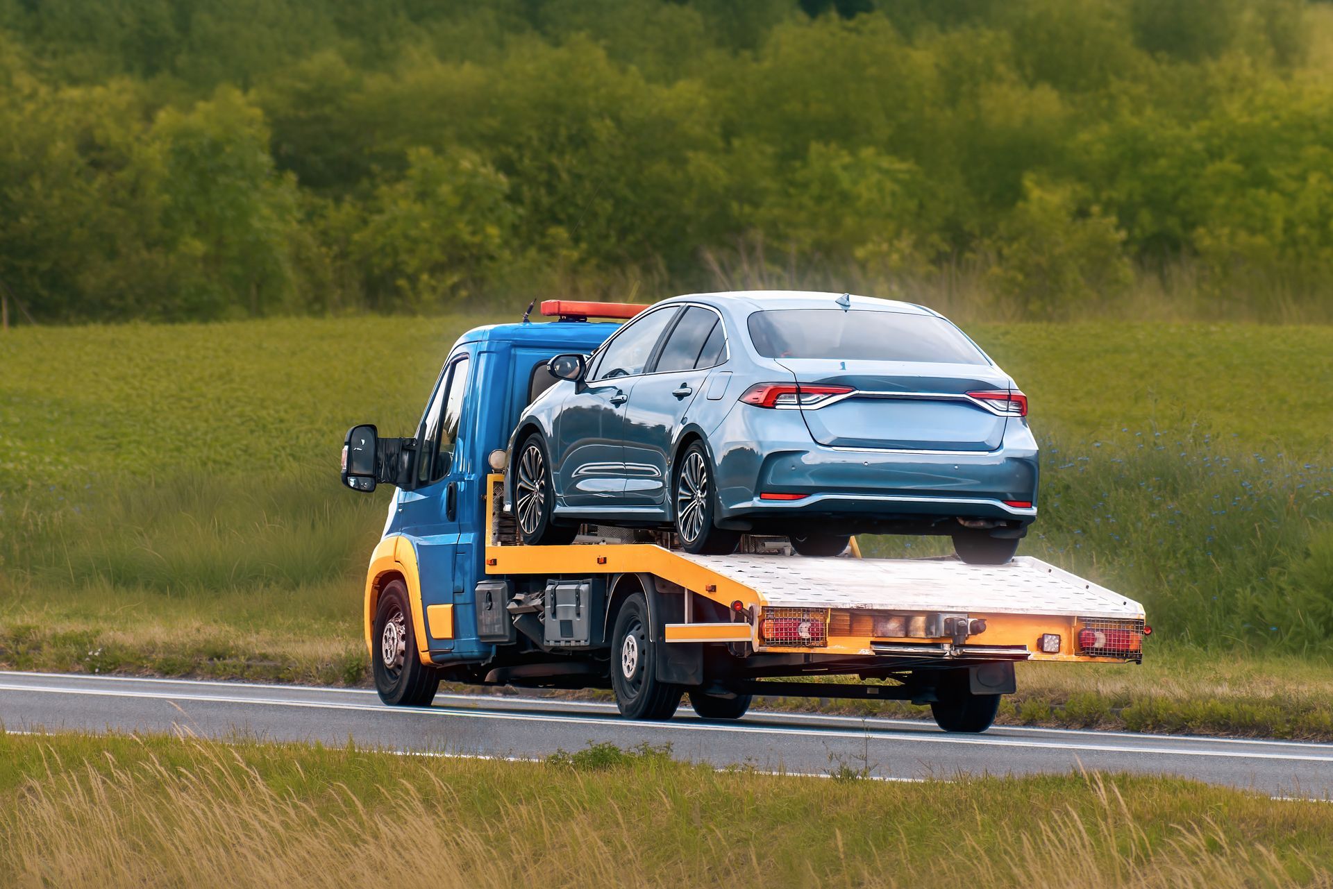 A blue car on top of a tow truck, showcasing professional towing services. A blue car on top of a tow truck, showcasing professional towing services.