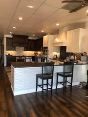 Modern kitchen with dark wood cabinets, white island, two bar stools, and hardwood floor
