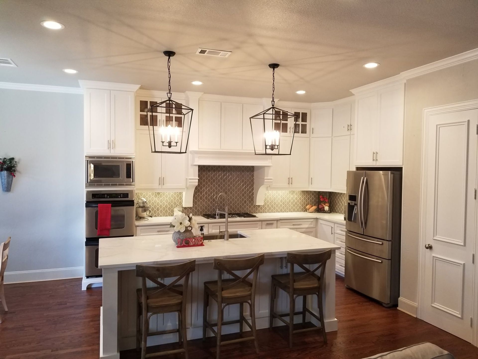 Bright modern kitchen with white cabinets, island, pendant lights, and stainless steel appliances
