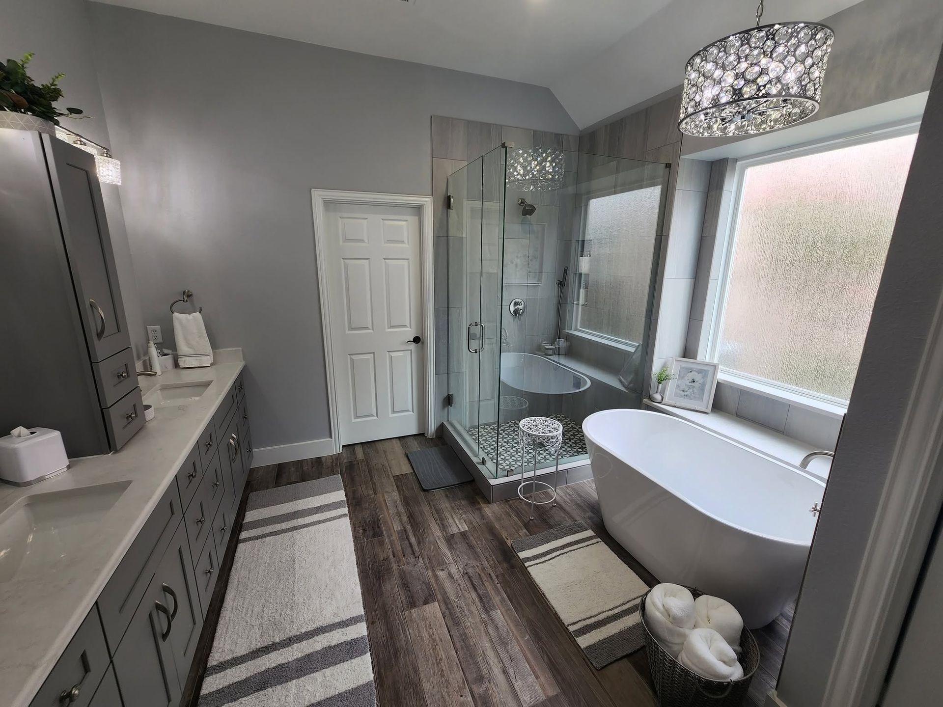 Modern bathroom with double vanity, freestanding tub, walk-in shower, and gray-white decor.