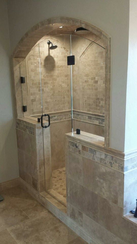 Walk-in tiled shower with glass door, built-in bench, and showerhead in a bathroom alcove