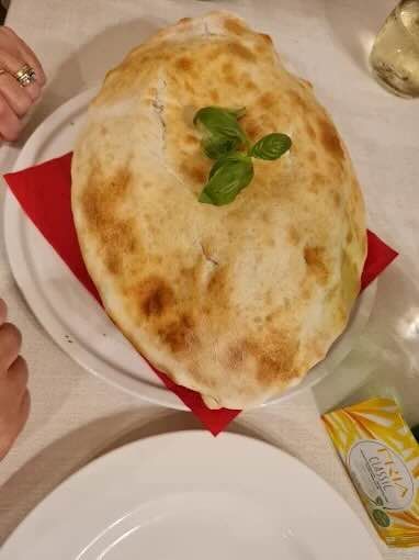 Calzone su un piatto con tovagliolo rosso, guarnito con basilico.