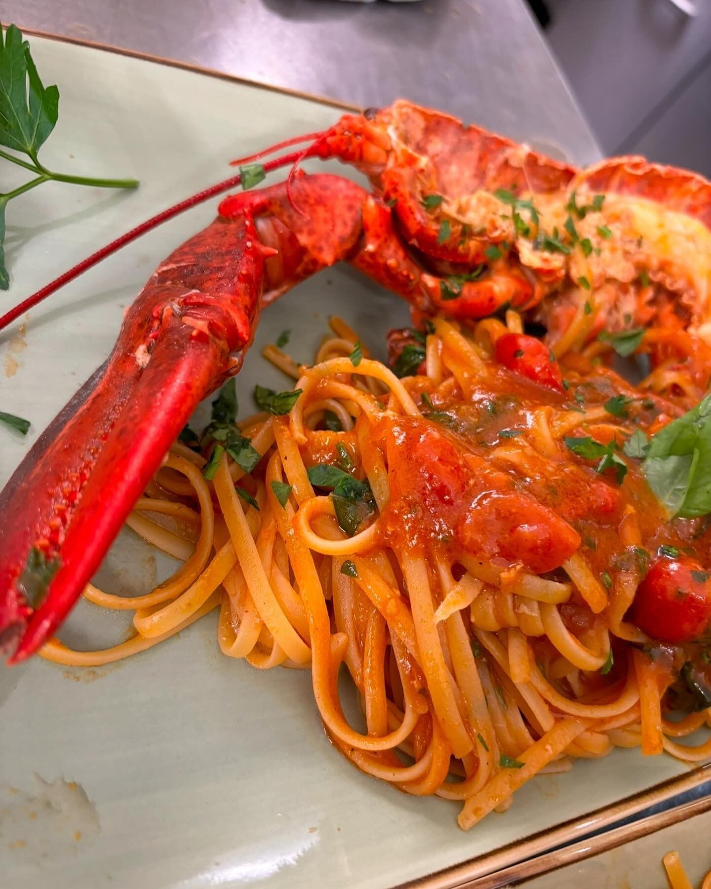 Piatto di pasta all'astice: astice rosso su linguine con salsa di pomodoro, guarnito con prezzemolo.