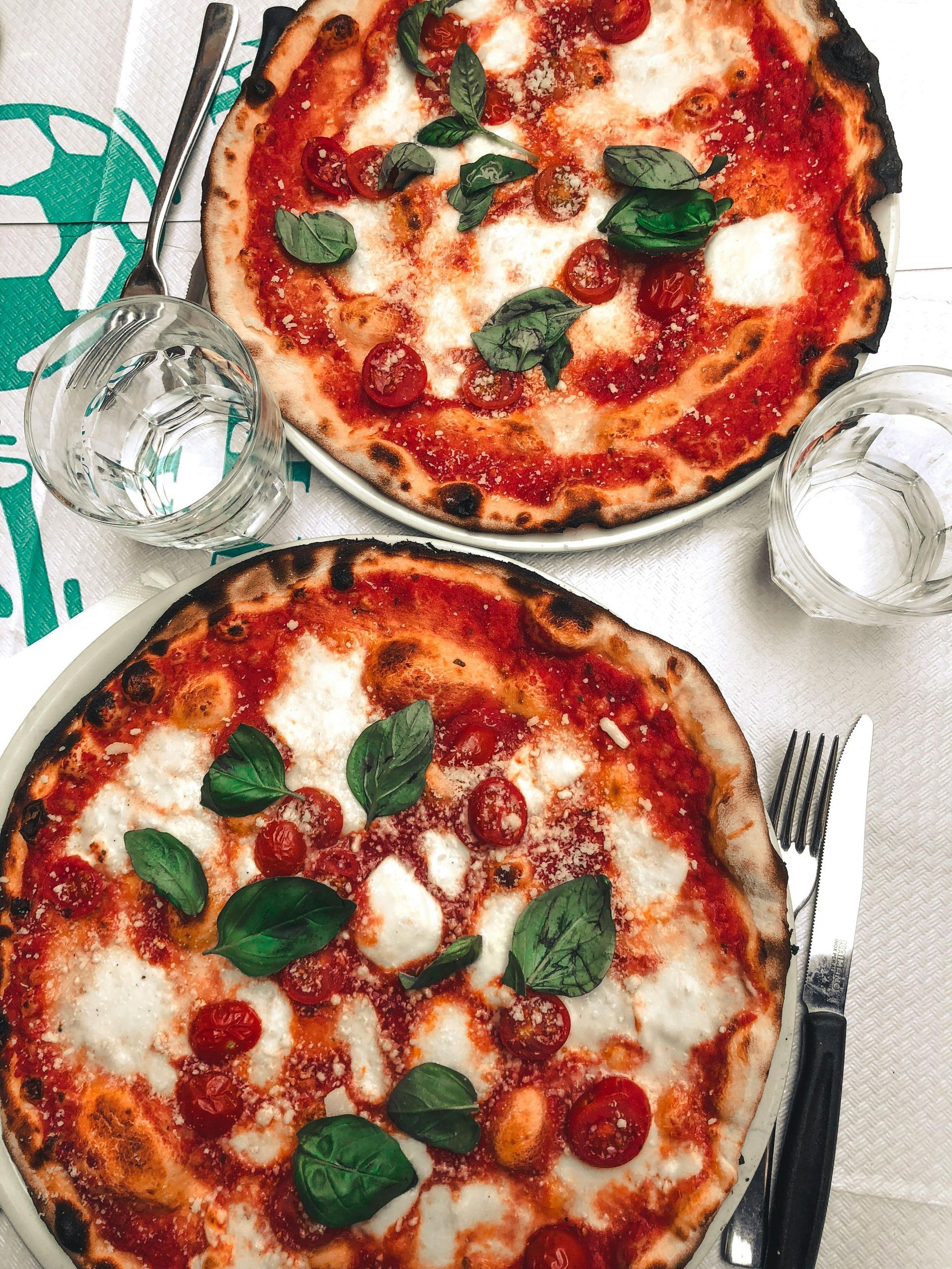 Due pizze con salsa di pomodoro, mozzarella, basilico e pomodorini.
