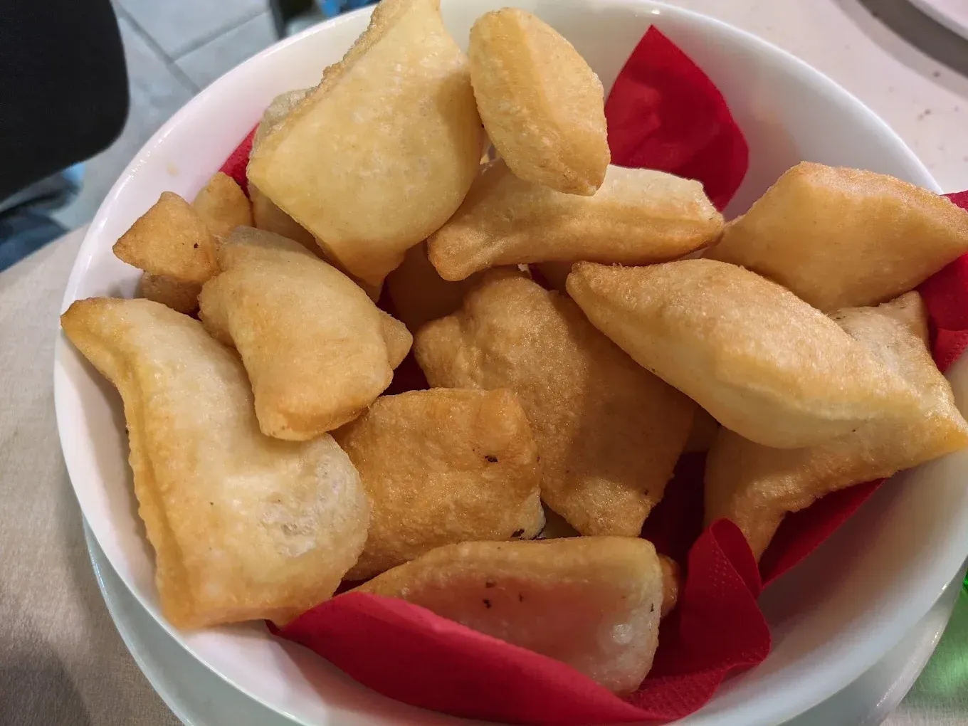 Una ciotola di dolci dorati e fritti, serviti con tovaglioli rossi.
