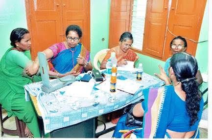 Women sitting around a table, sharing a meal and conversation in a bright room with orange doors
