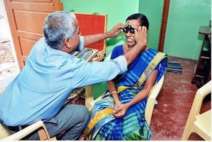 Eye exam in progress as a doctor checks a seated patient’s vision with a handheld tool.