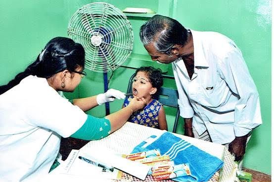Doctor checking a child's throat as a nurse assists in a clinic room