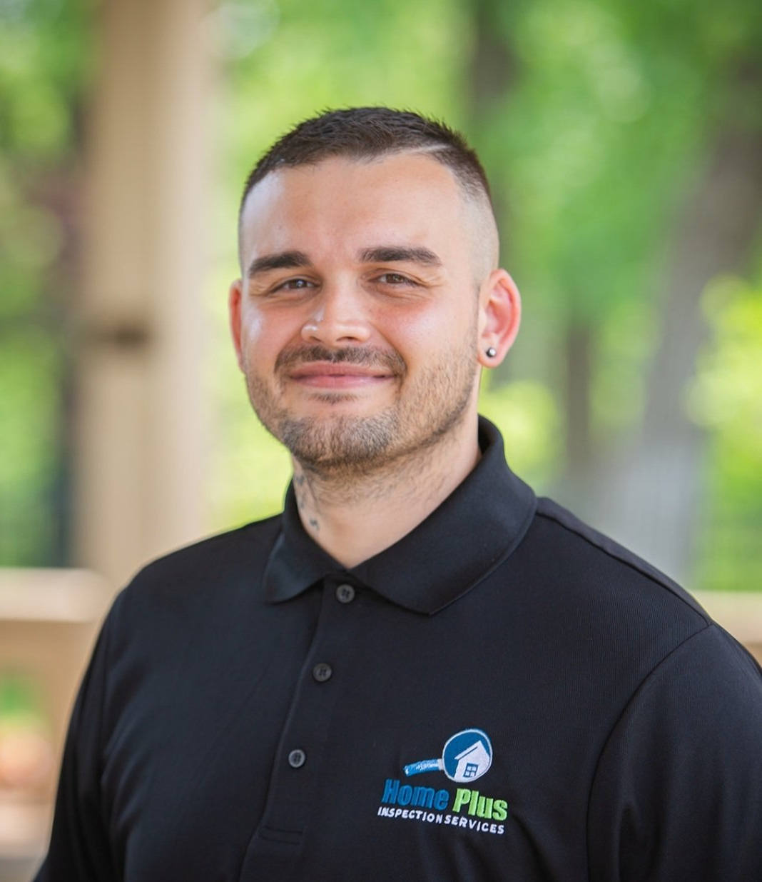 A man wearing a black polo shirt is smiling for the camera.
