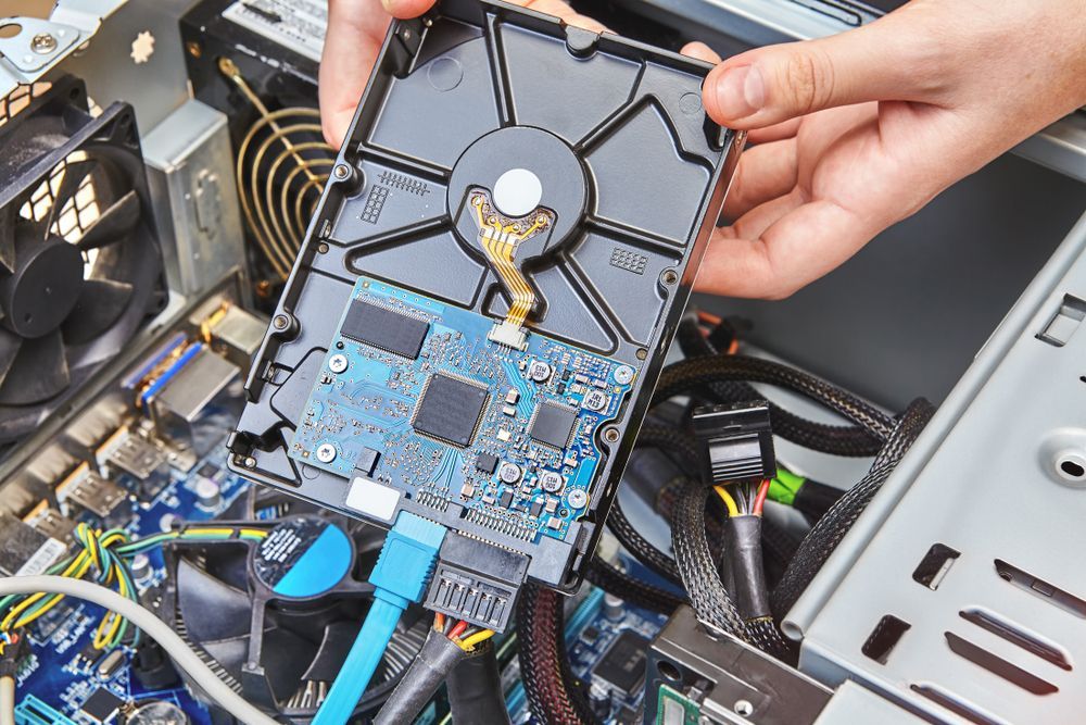 Hands Holding a Hard Drive Over a Computer's Open Interior — Tech Aid In Moffat Beach, QLD