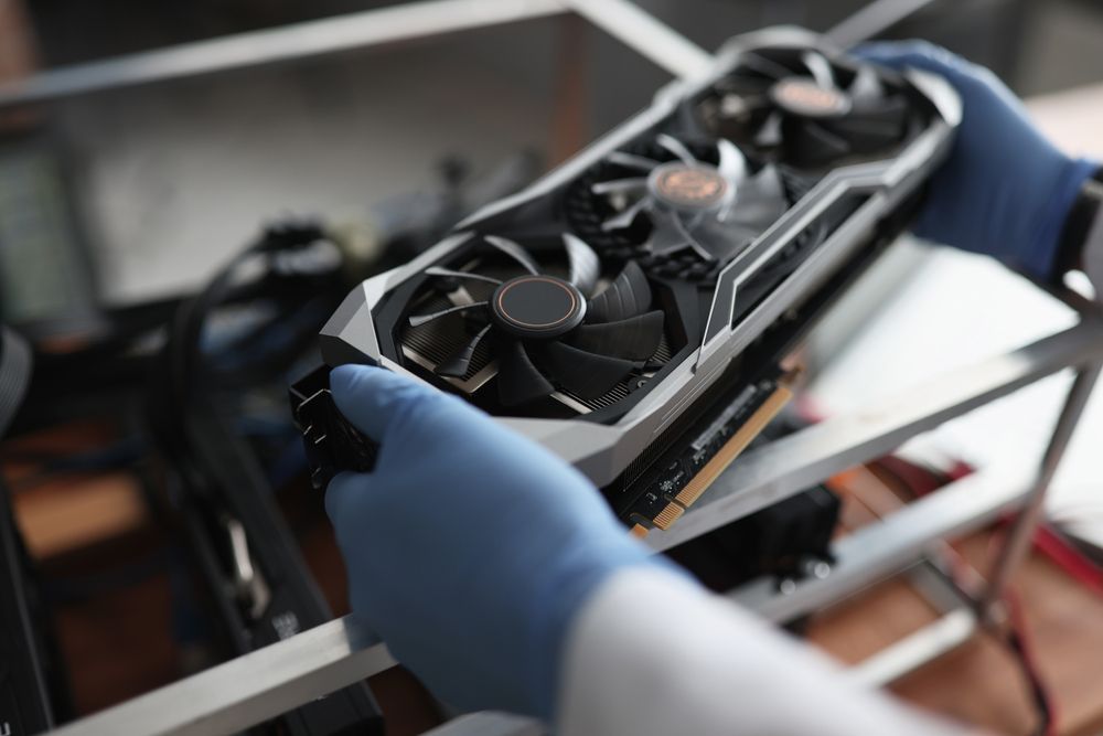 A Person Wearing Blue Gloves Holds a Black and Silver Graphics Card — Tech Aid In Moffat Beach, QLD
