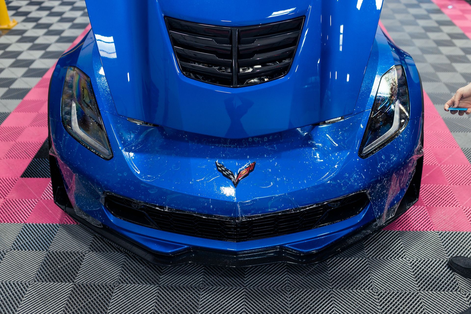 A blue corvette is sitting on a checkered floor.