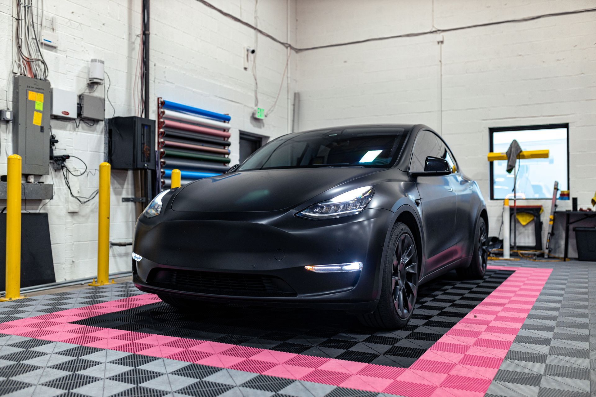 A black tesla model y is parked in a garage.