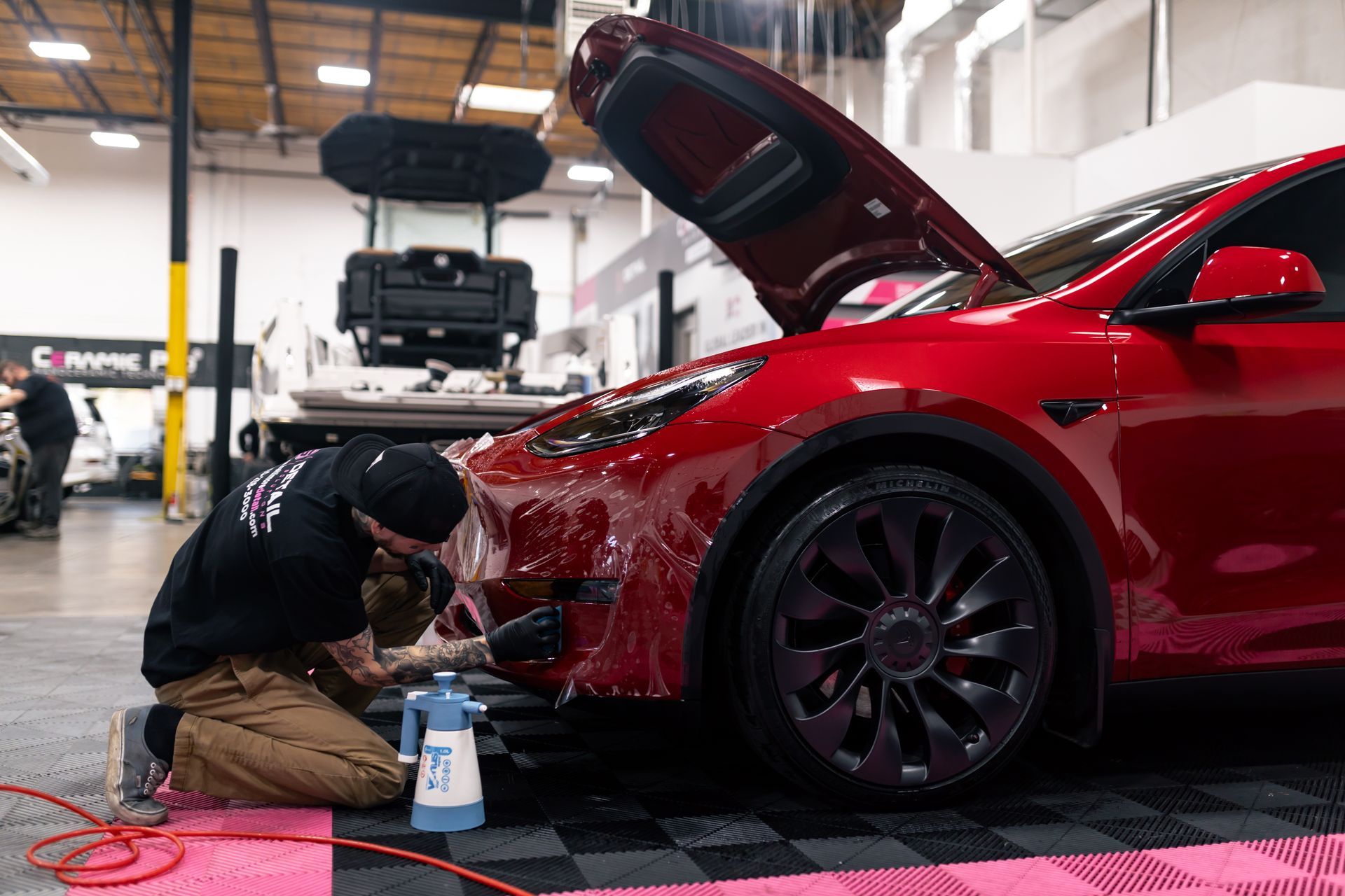 A man is cleaning the hood of a white car.