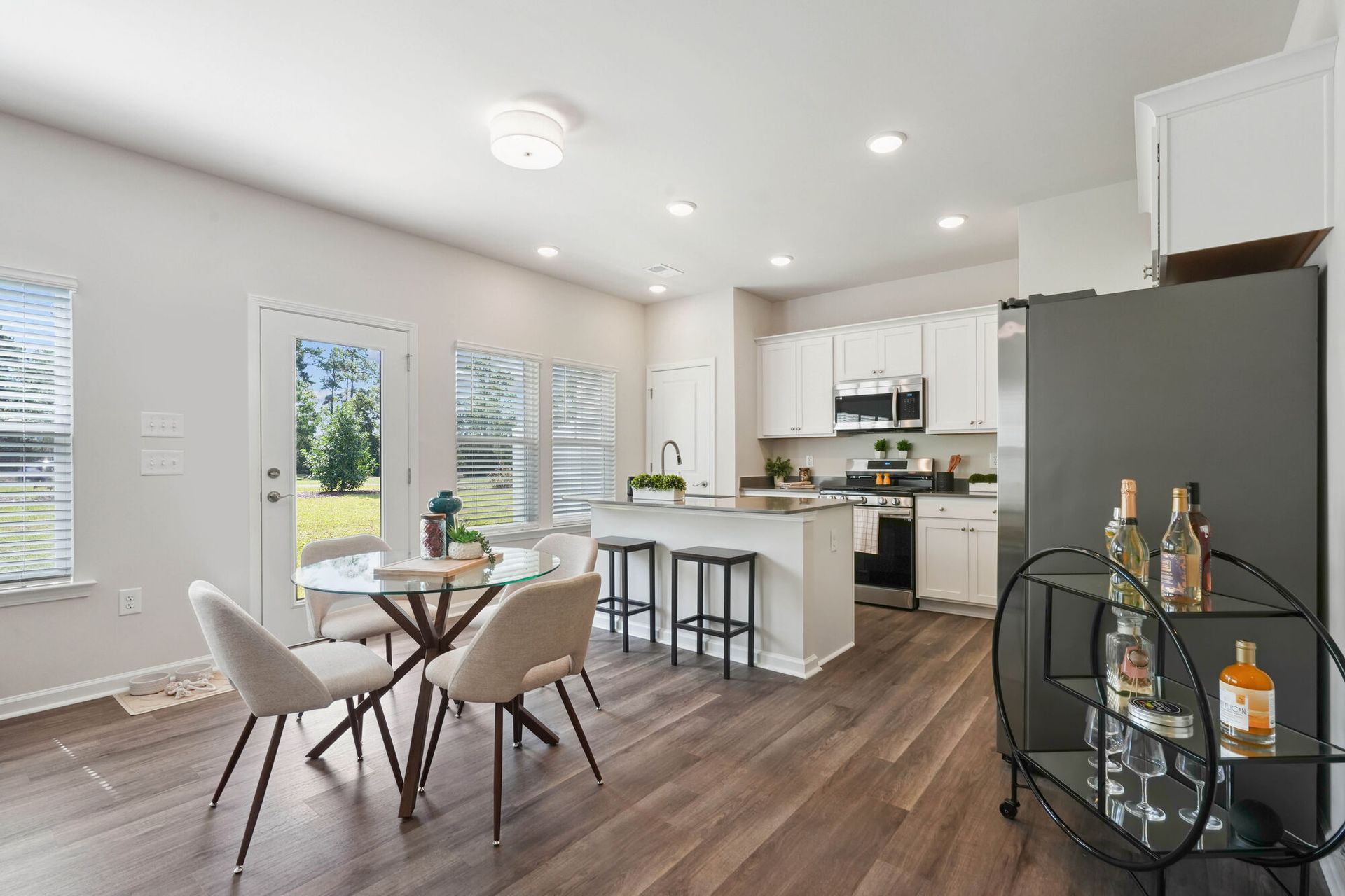 Open-concept kitchen and dining area with white cabinets, island, table, and dark flooring.