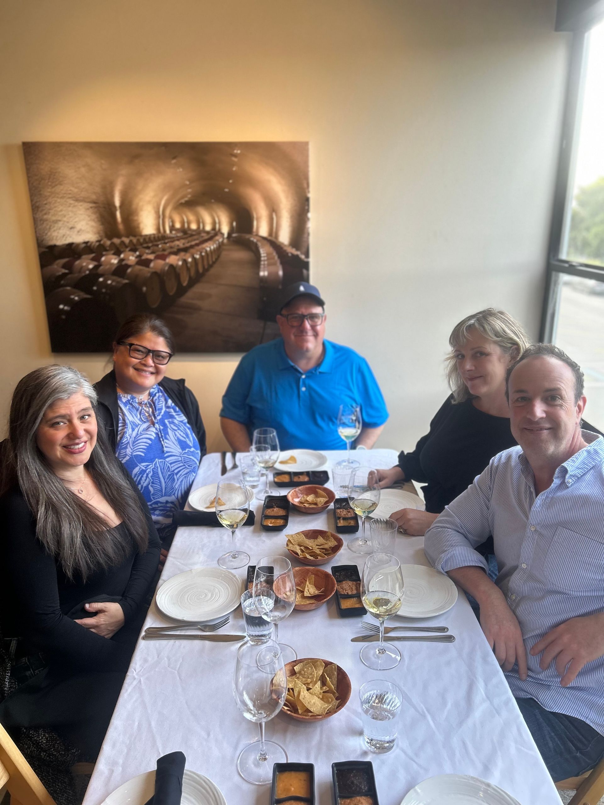 A group of people are sitting at a table with plates and glasses of wine