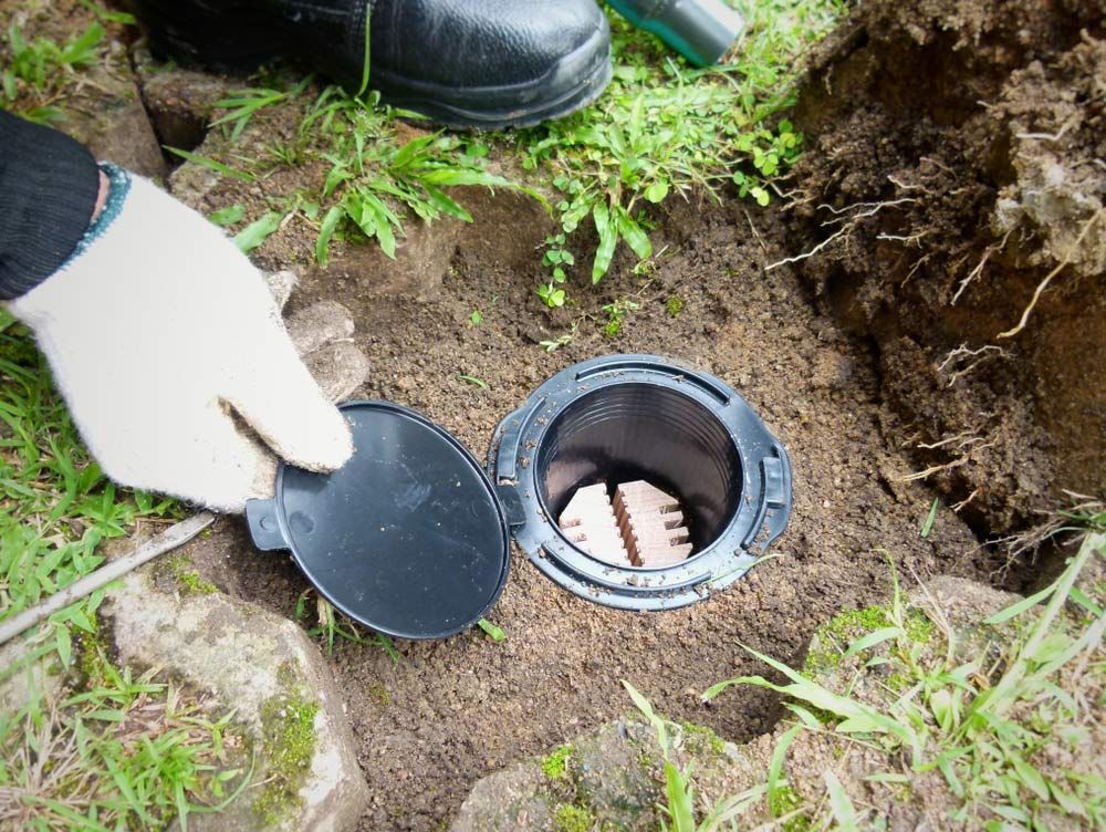 A Person Is Digging A Hole In The Ground To Install A Drain — ASAP Pest Control in Gold Coast, QLD