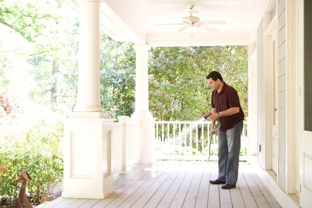 A Man Is Standing On A Porch Looking At Something — ASAP Pest Control in Doolandella, QLD