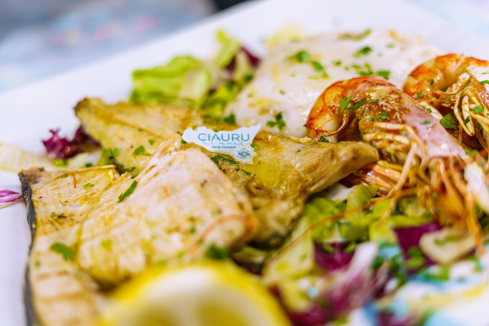 Piatto di pesce: pesce alla griglia, gamberi, carciofi e insalata su un piatto bianco.