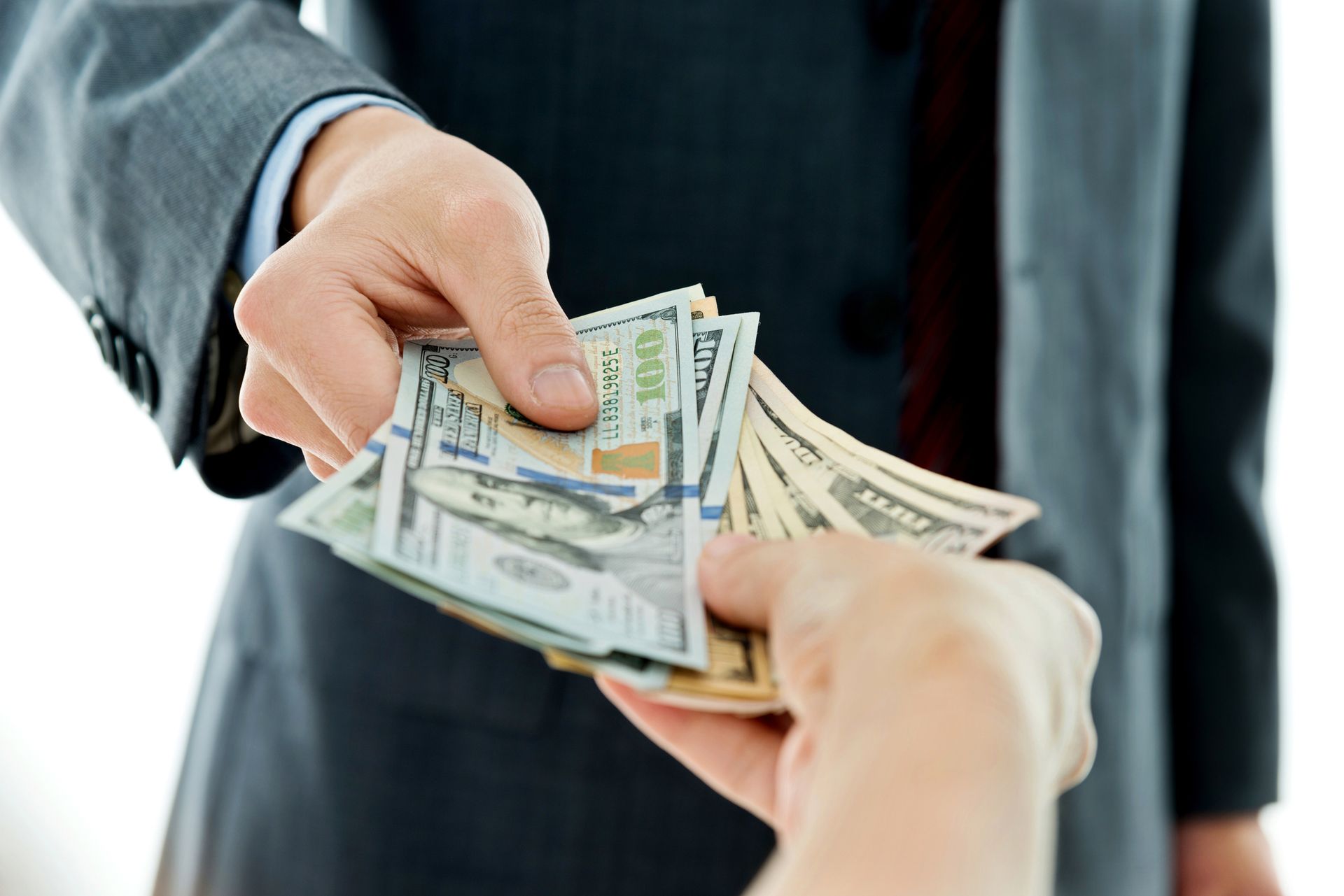 Close-up of businessman's hands giving money. Hands exchanging a stack of U.S. dollar bills in a business setting