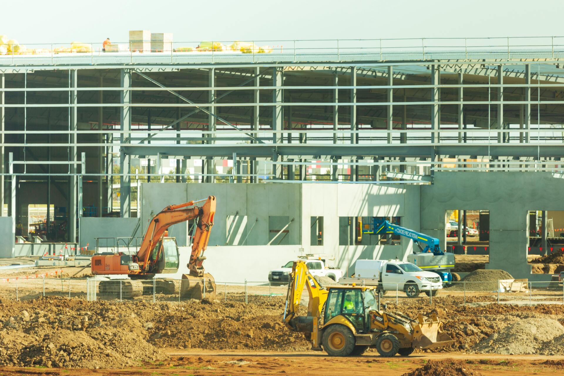 A large building is being built with a lot of machinery in front of it.