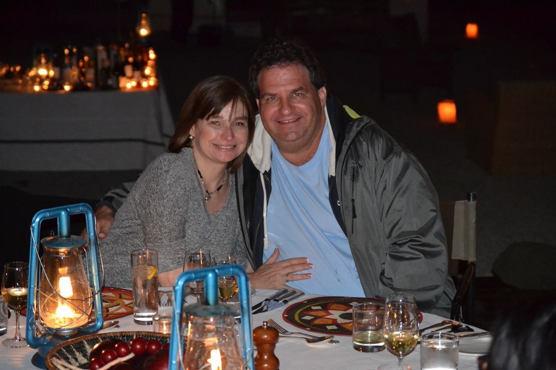 A man and a woman are posing for a picture at a table with lanterns.