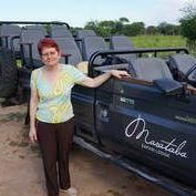 A woman is standing next to a jeep in a field.